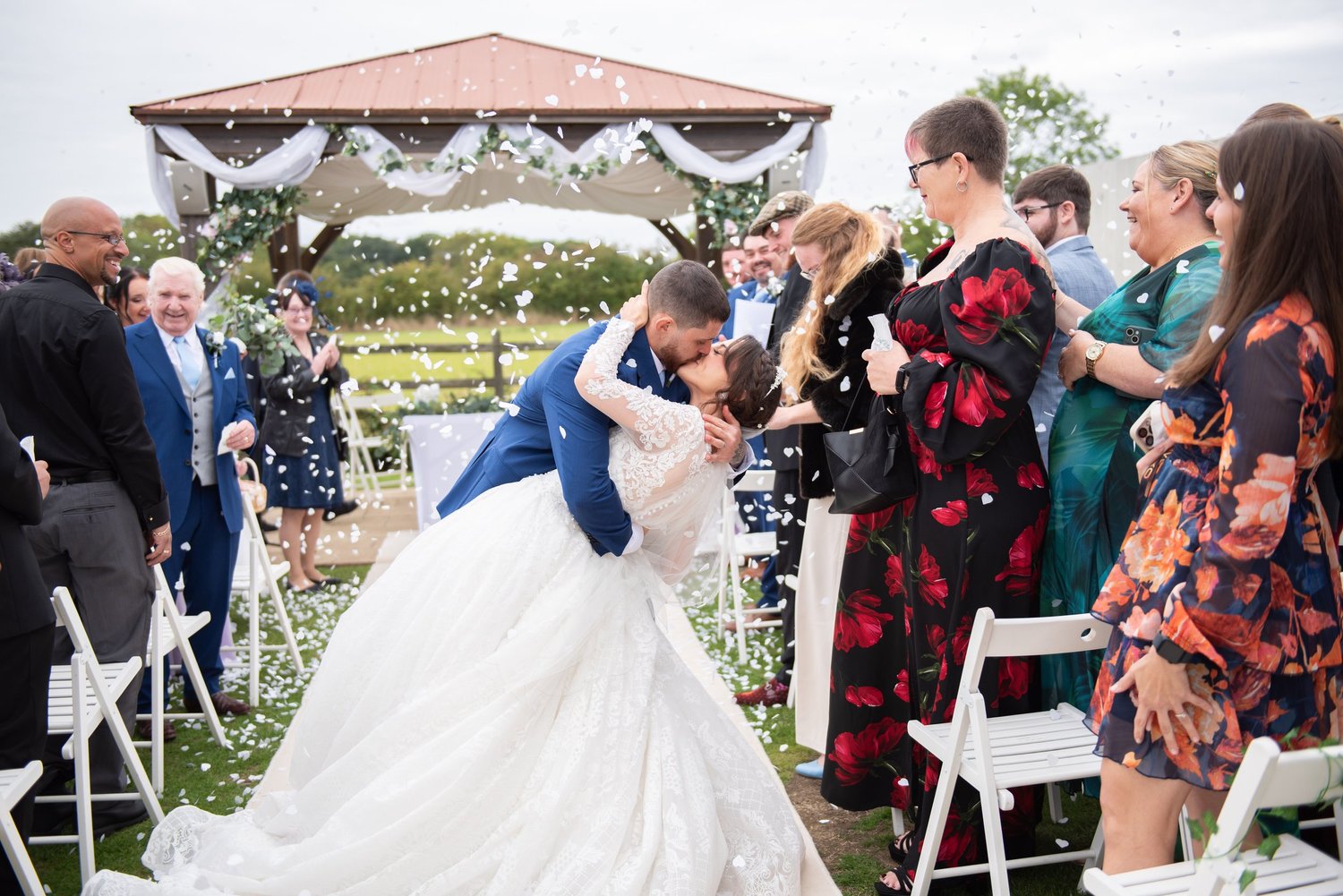 Groom dipping his bride for a kiss as guests shower them with confetti